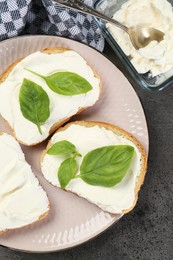 Photo of Delicious sandwiches with cream cheese and basil leaves on grey table, flat lay