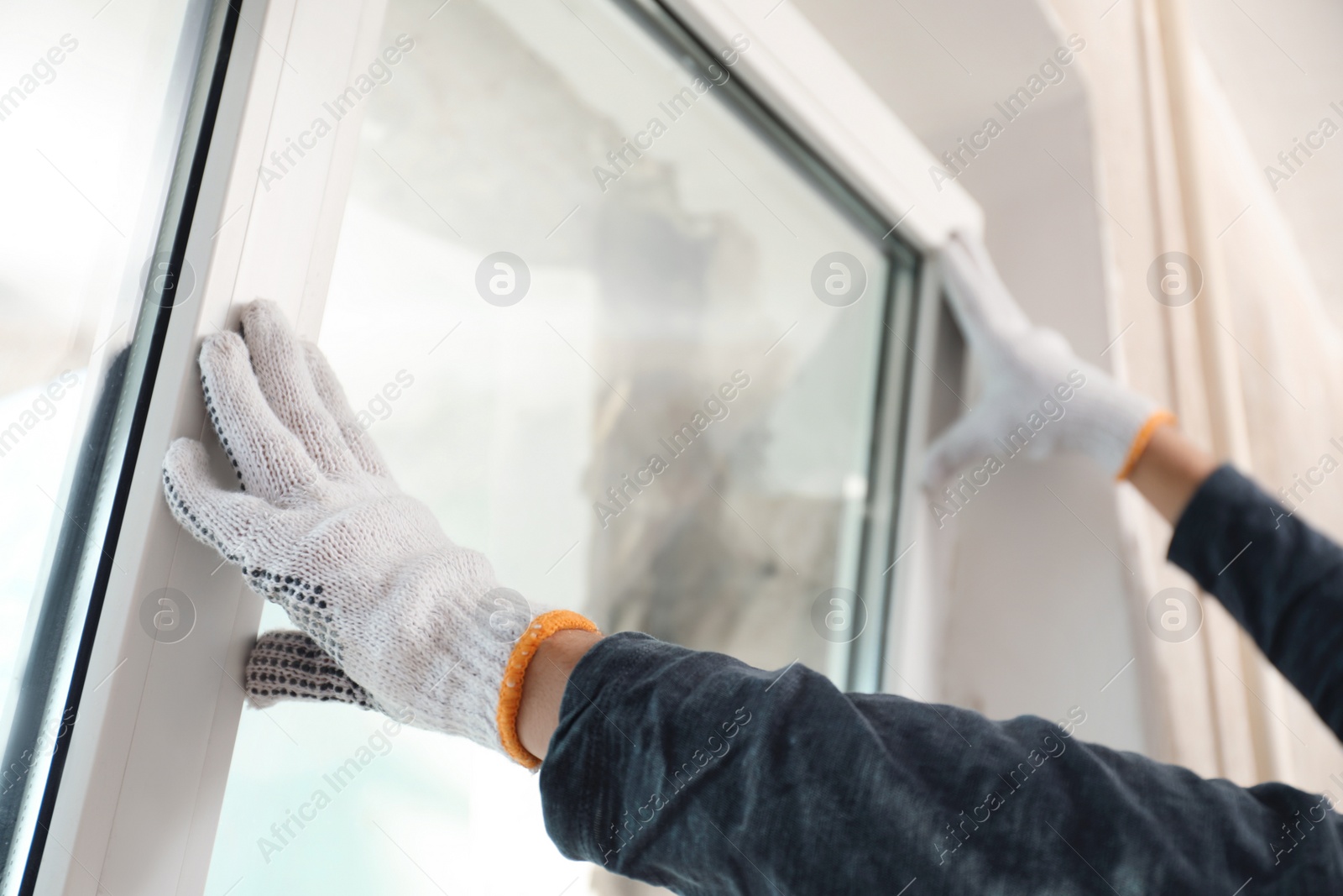 Photo of Worker installing plastic window indoors, closeup view