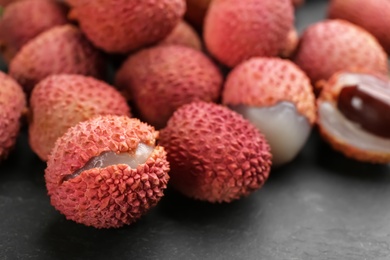 Photo of Fresh ripe lychee fruits on black table, closeup