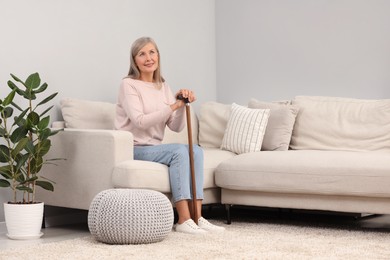 Photo of Mature woman with walking cane on sofa at home