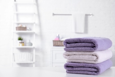 Photo of Stack of fresh towels on table in bathroom. Space for text