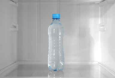 Photo of Bottle of water on shelf inside modern refrigerator
