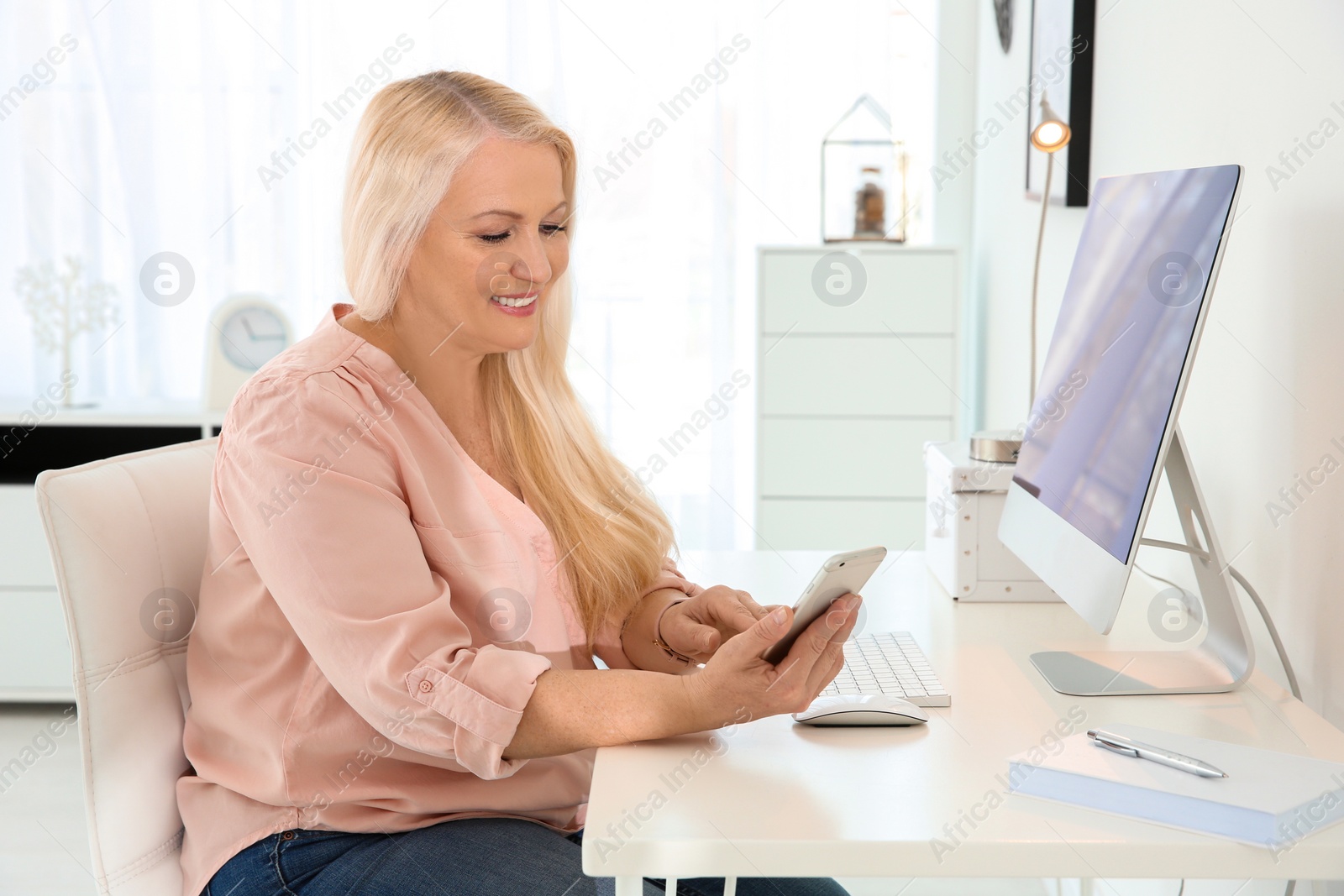 Photo of Mature woman using mobile phone at workplace