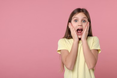 Photo of Portrait of surprised girl on pink background. Space for text