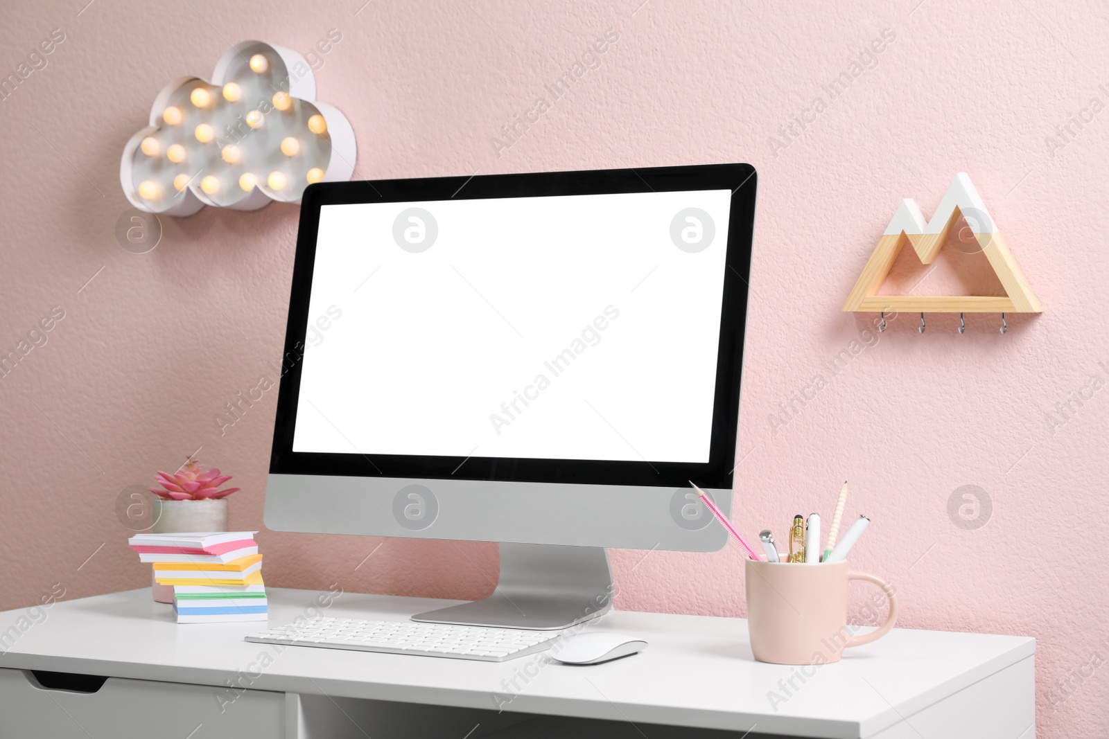 Photo of Comfortable workplace with modern computer on table near pink wall. Space for design