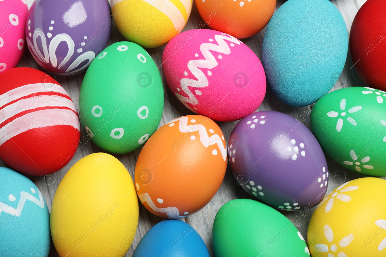 Photo of Many bright Easter eggs on wooden background, top view