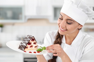 Photo of Professional female chef with plate of delicious dessert in kitchen