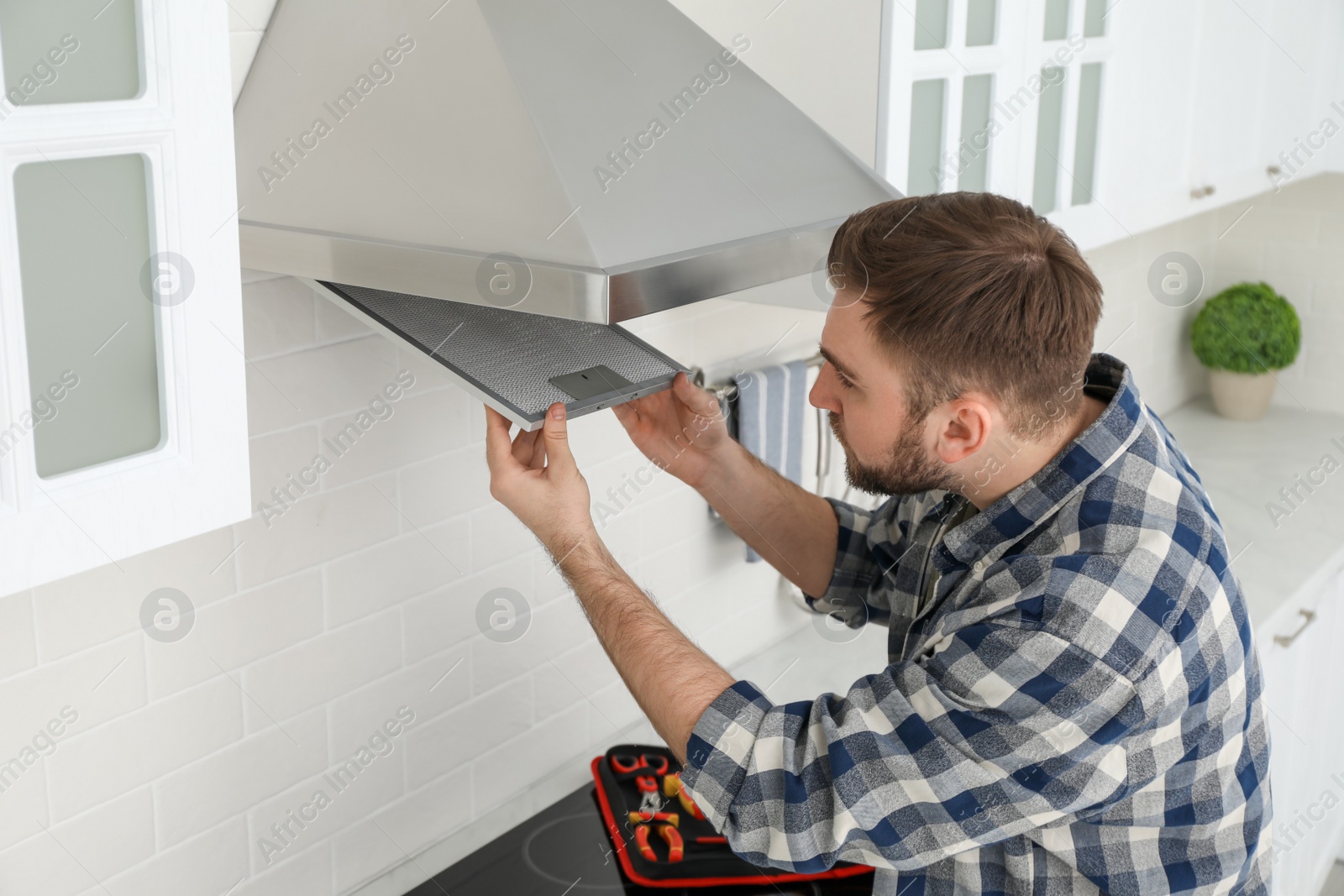 Photo of Man repairing modern cooker hood in kitchen