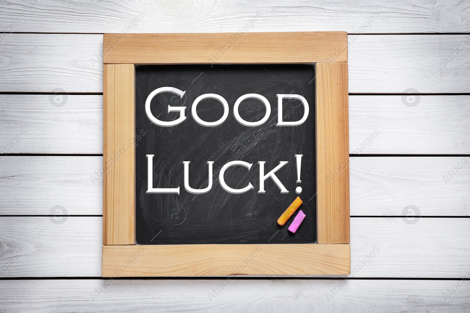 Image of Blackboard with phrase GOOD LUCK on white wooden background, top view