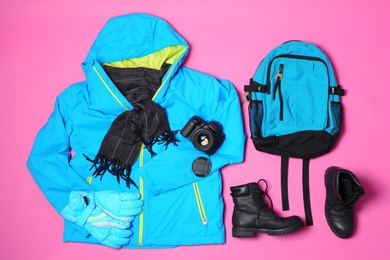 Flat lay composition with warm clothes for winter vacation on color background