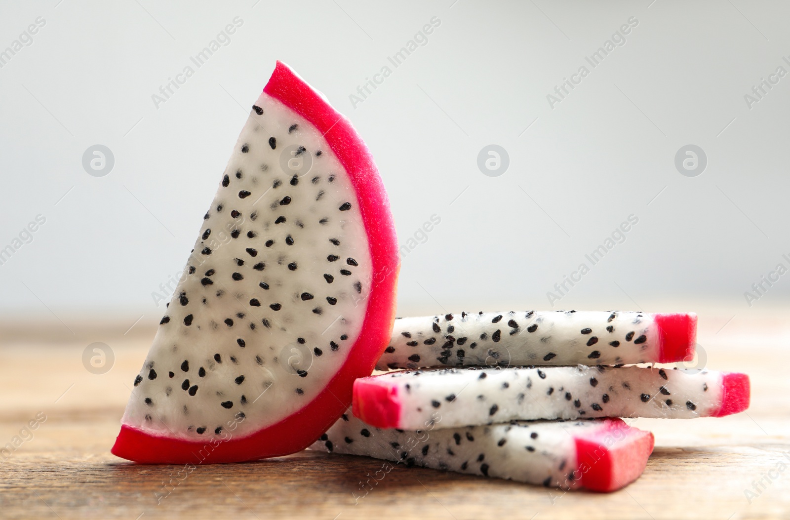 Photo of Slices of delicious ripe dragon fruit (pitahaya) on wooden table