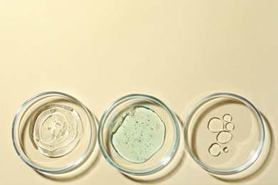 Many Petri dishes and cosmetic products on beige background, flat lay. Space for text
