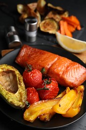 Photo of Delicious cooked salmon and vegetables on black table, closeup. Healthy meals from air fryer