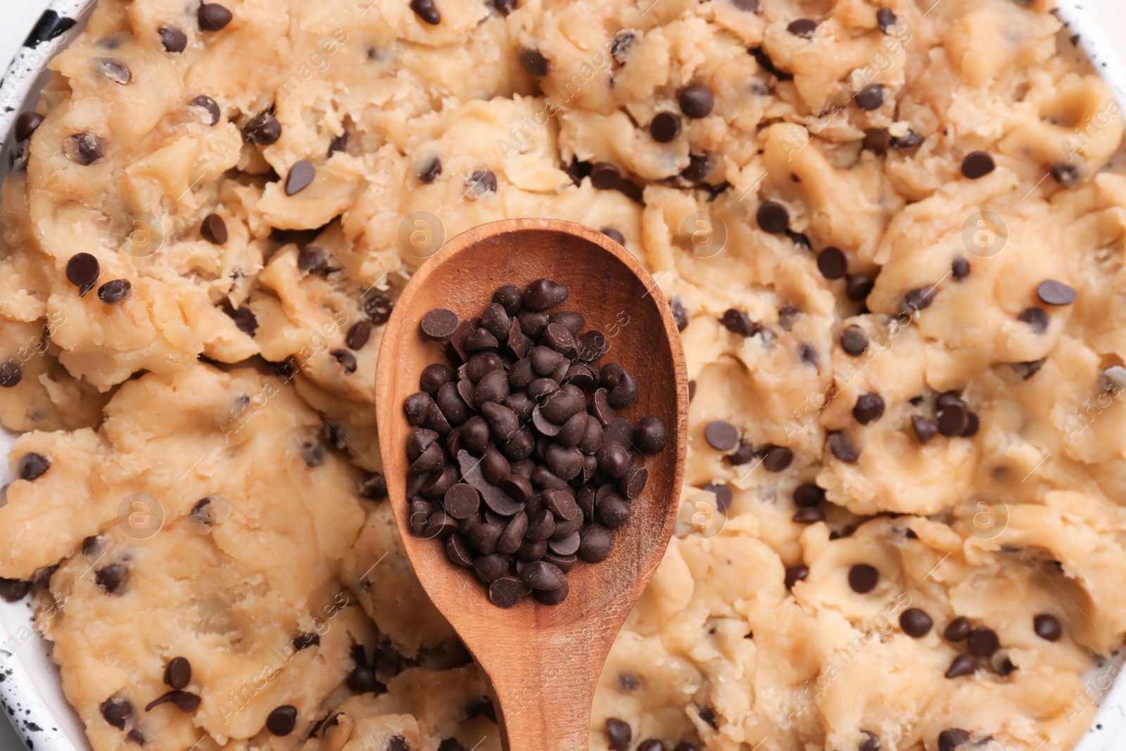 Photo of Cookie dough with chocolate chips and wooden spoon, closeup