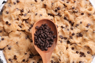 Photo of Cookie dough with chocolate chips and wooden spoon, closeup