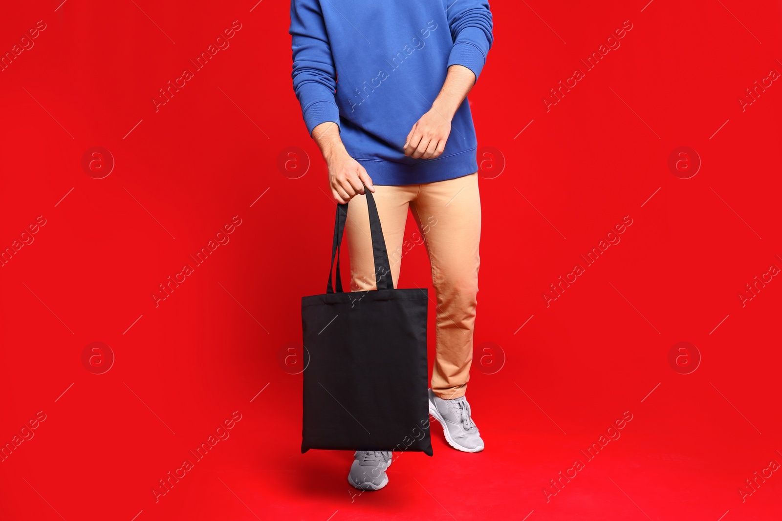 Photo of Young man with eco bag on red background, closeup