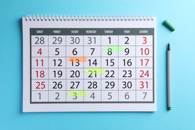 Timetable. Calendar with marked dates and pen on light blue background, top view