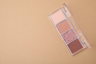 Photo of Beautiful eye shadow palette on beige background, top view. Space for text
