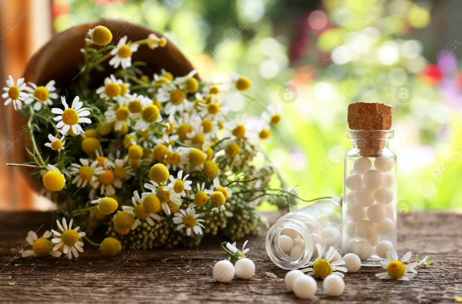 Photo of Bottles of homeopathic remedy and beautiful flowers on wooden table