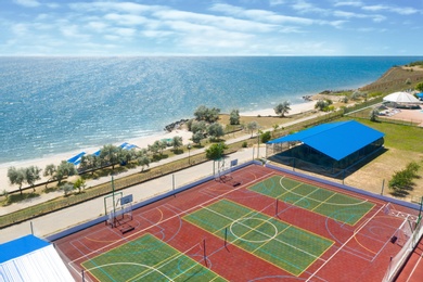 Image of Outdoor sports complex near sea on sunny day, aerial view