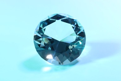 Photo of Beautiful dazzling diamond on light blue background, closeup