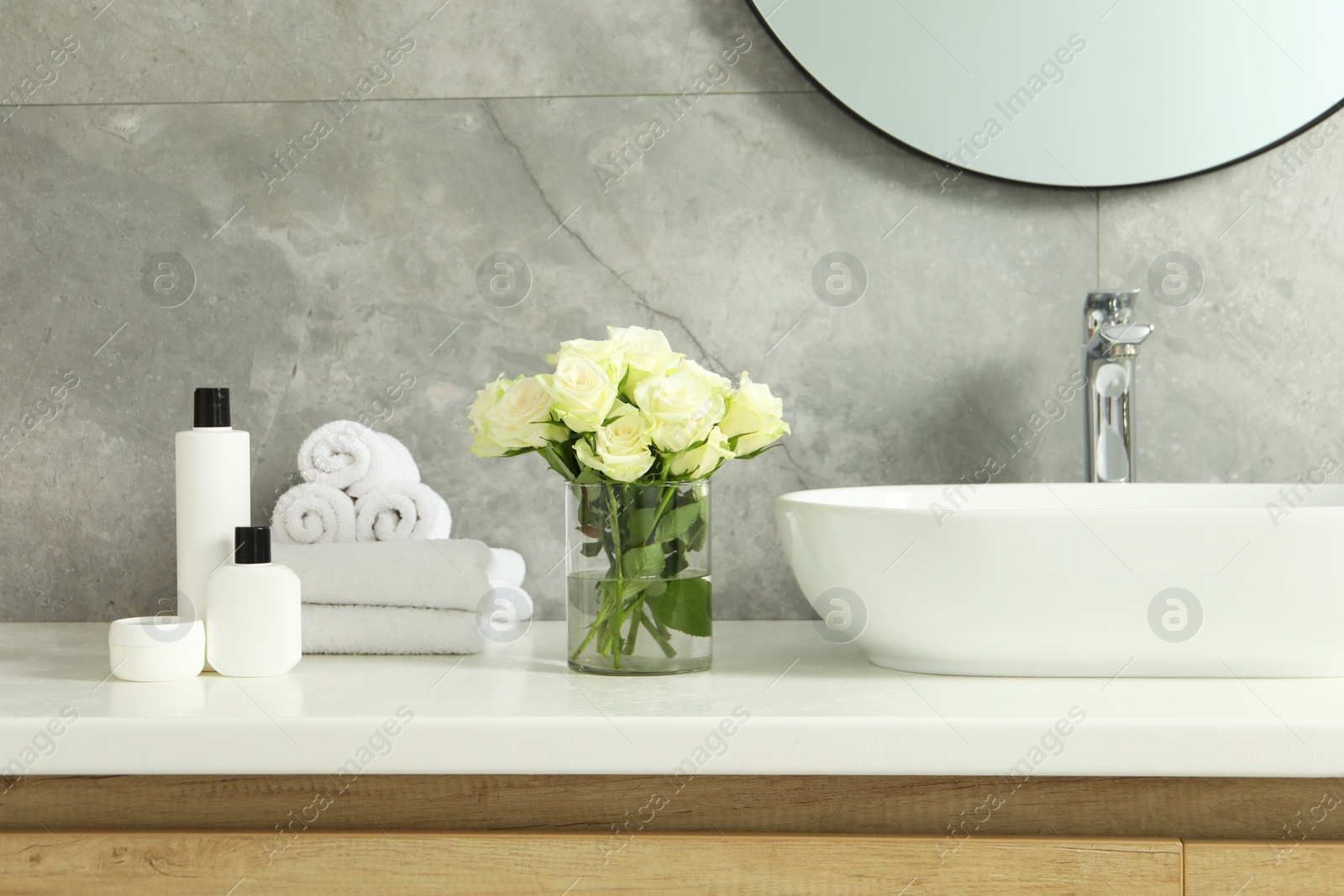 Photo of Beautiful roses and bath accessories near sink in bathroom