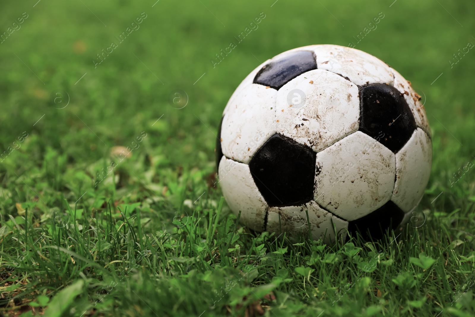 Photo of Dirty soccer ball on green grass outdoors, space for text