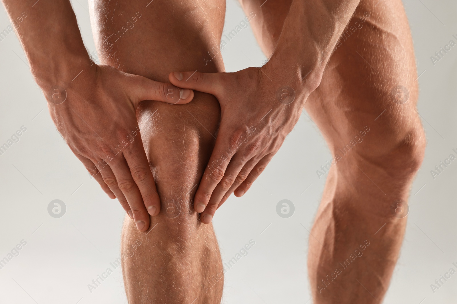 Photo of Man touching his knee on light grey background, closeup