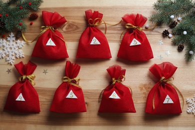 Photo of New Year advent calendar with gifts and Christmas decor on wooden background, flat lay