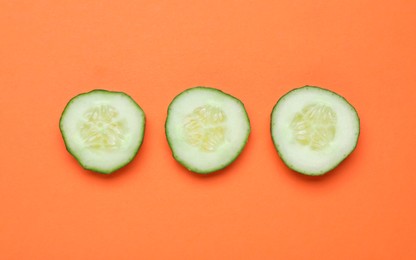 Photo of Slices of fresh ripe cucumber on orange background, flat lay