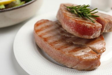 Delicious tuna steaks with rosemary on white table, closeup