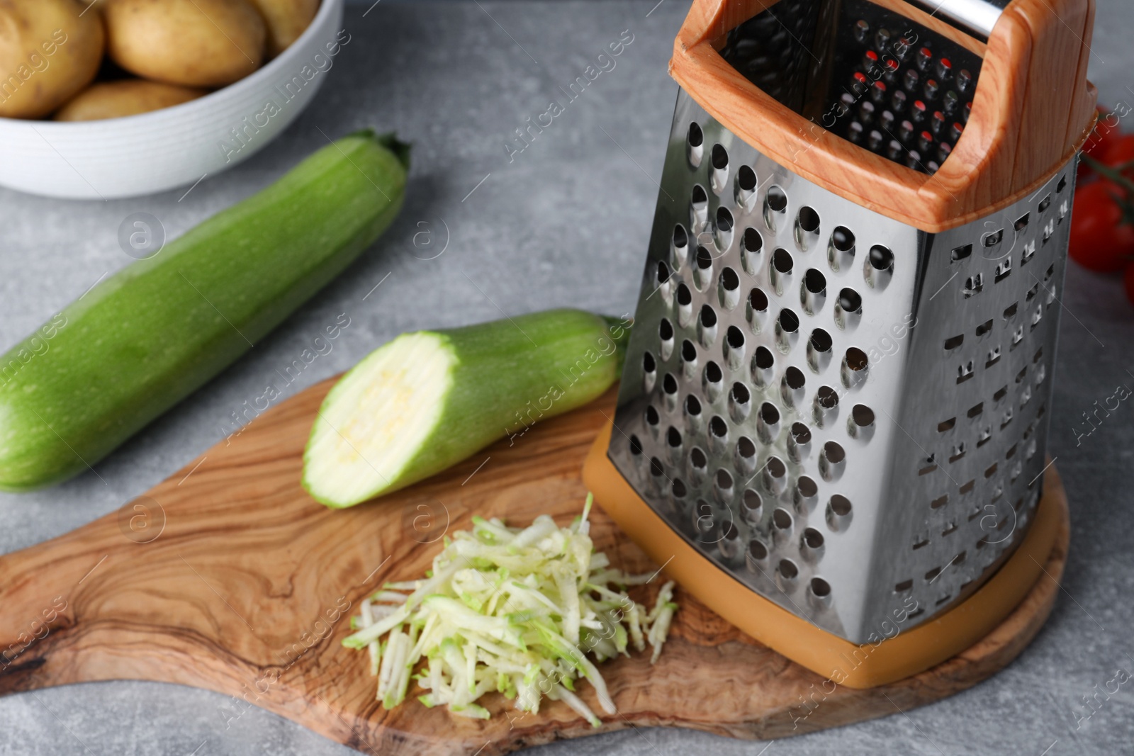 Photo of Grater and fresh zucchinis on grey table