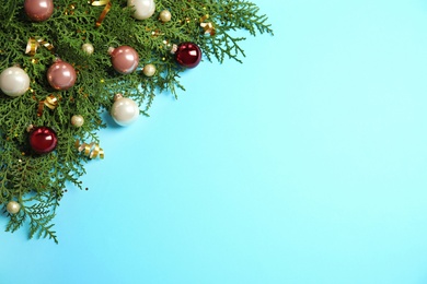 Fir tree branches with Christmas decoration on light blue background, flat lay. Space for text