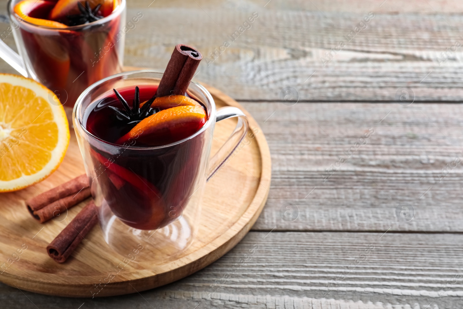 Photo of Aromatic mulled wine on wooden table, space for text