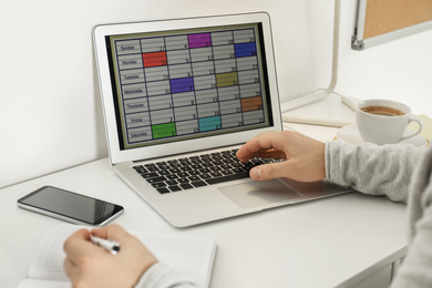 Young man using calendar app on laptop in office, closeup