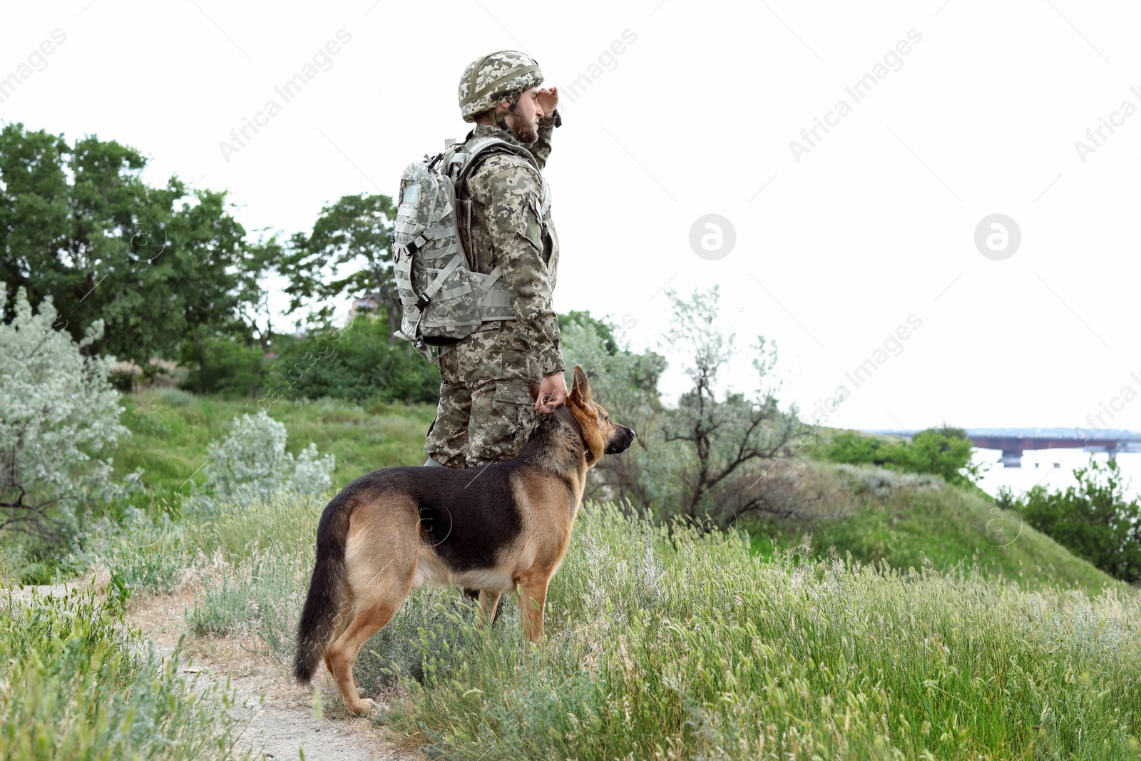 Photo of Man in military uniform with German shepherd dog outdoors