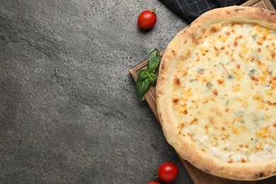 Delicious cheese pizza, basil and tomatoes on dark grey table, flat lay. Space for text