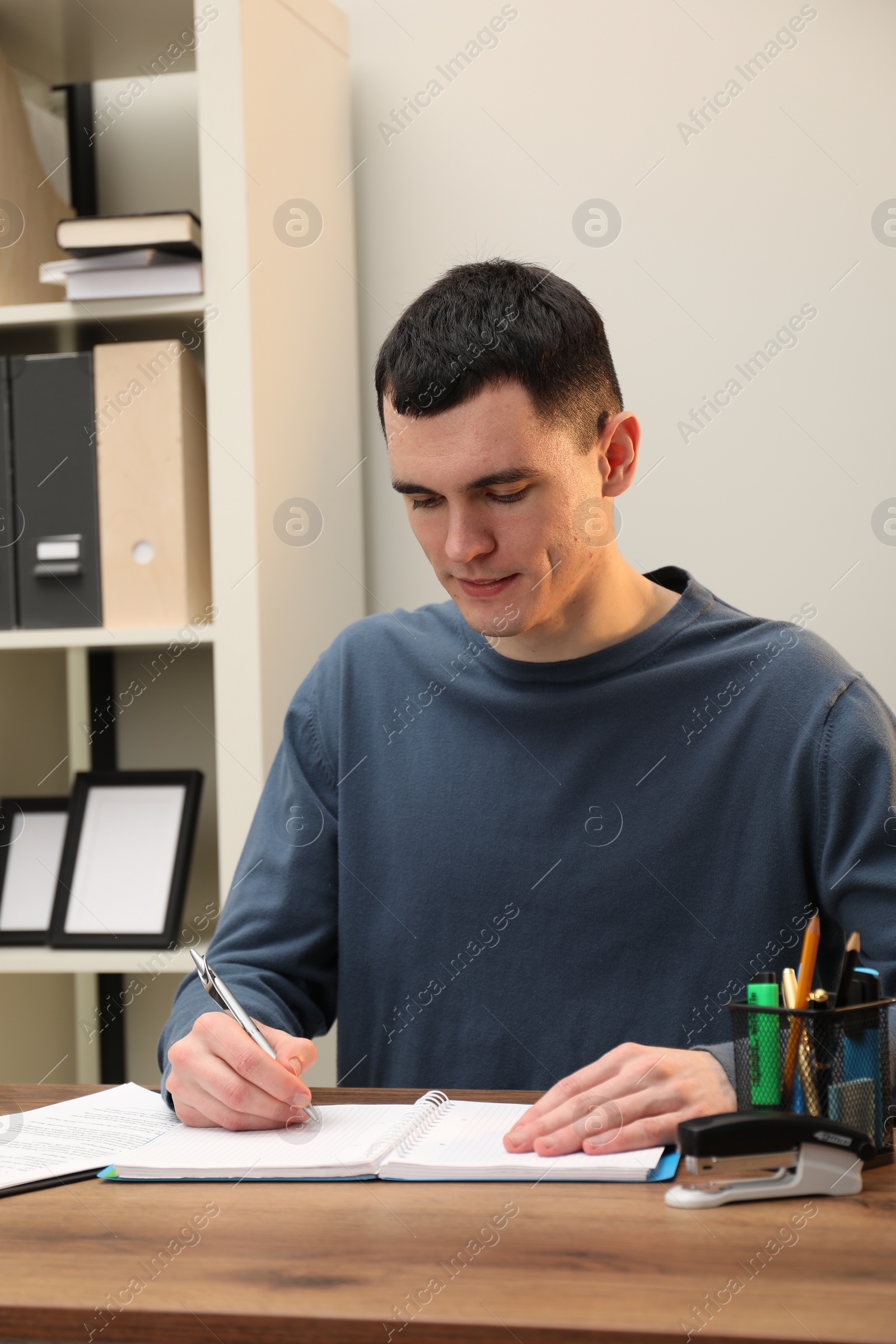 Photo of Man taking notes at wooden table in office