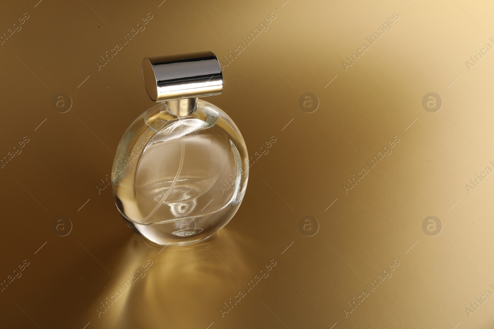 Photo of Luxury women's perfume. Sunlit glass bottle on golden background, space for text