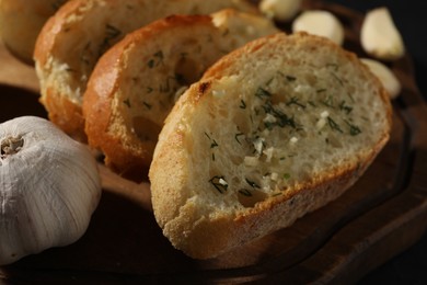 Tasty baguette with garlic and dill on wooden board, closeup