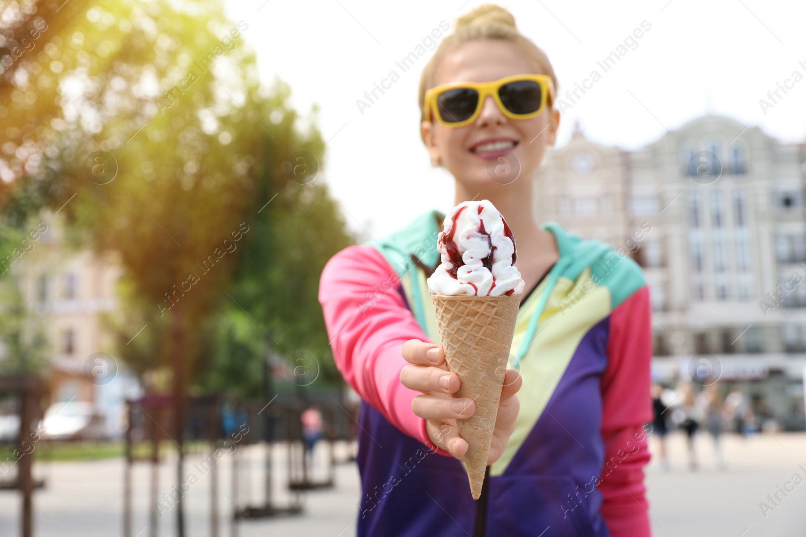 Photo of Young happy woman with ice cream cone on city street. Space for text