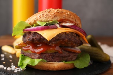 Photo of Tasty cheeseburger with patties and onion on table, closeup
