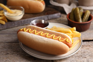 Photo of Delicious hot dog with ketchup, mustard and French fries on wooden table, closeup