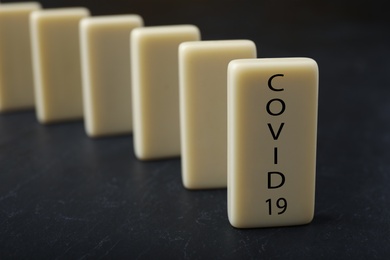 Photo of Domino tiles on black table, space for text. Spreading of coronavirus concept