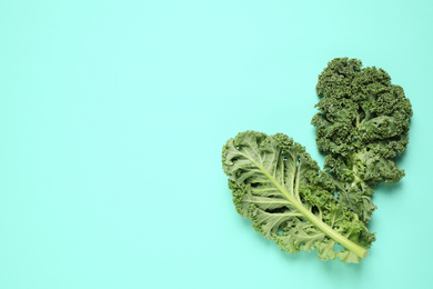 Photo of Fresh kale leaves on turquoise background, flat lay. Space for text