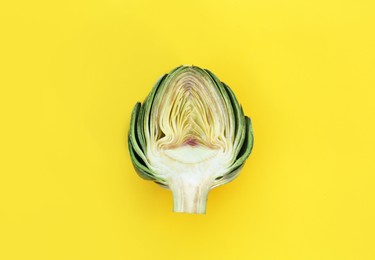 Half of fresh raw artichoke on pale yellow background, top view