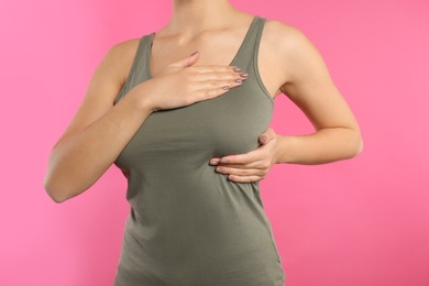 Photo of Woman checking her breast on color background, closeup