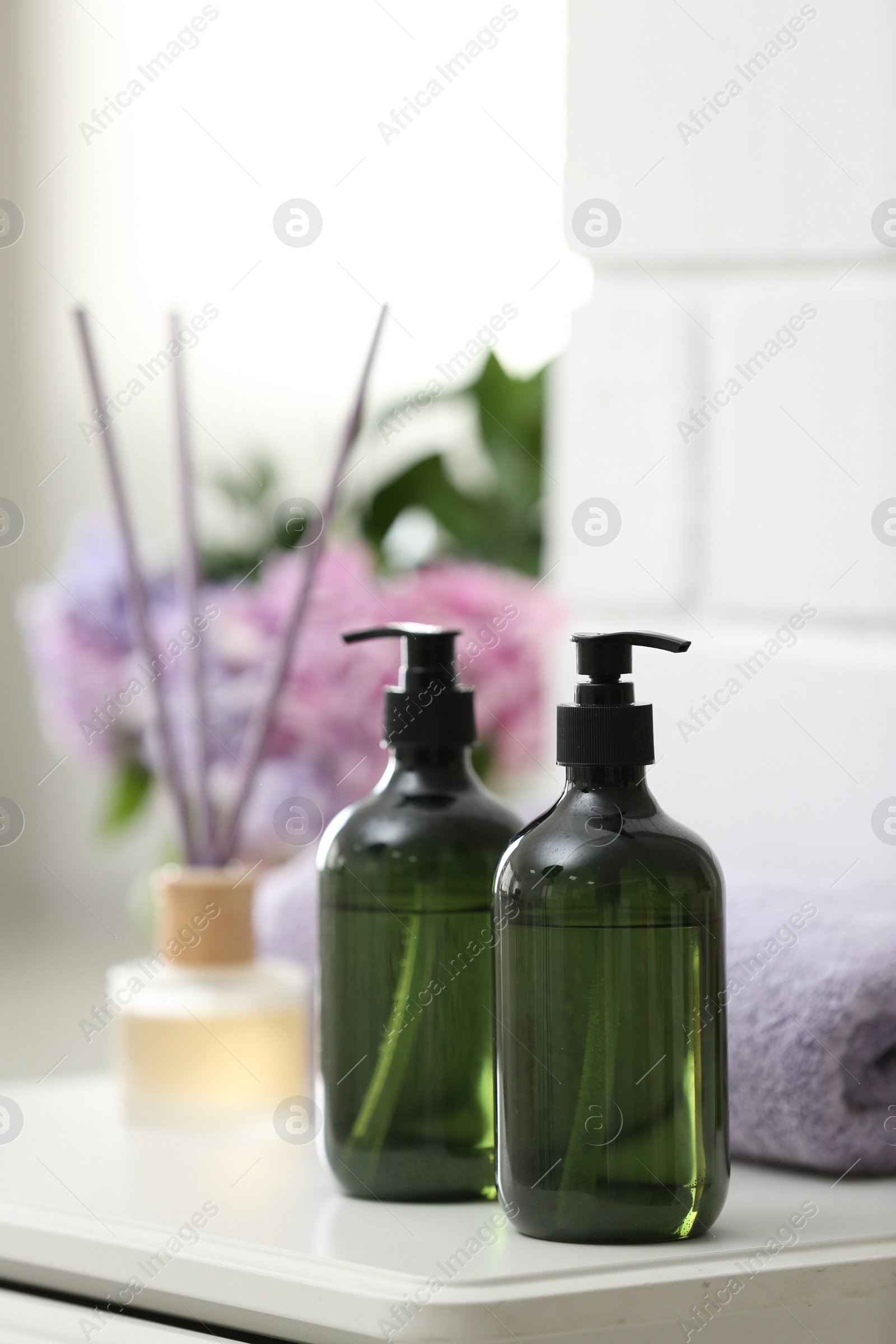 Photo of Soap dispensers and clean towel on white table