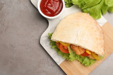Photo of Delicious pita sandwich with fried fish, pepper, tomatoes and lettuce on light grey table, flat lay. Space for text