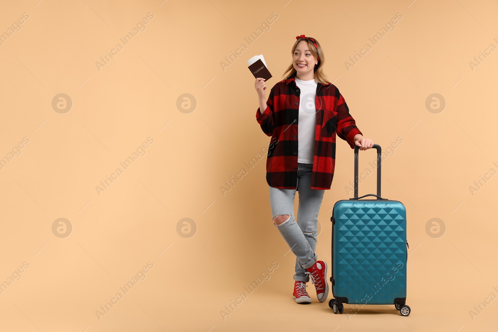 Photo of Happy young woman with passport, ticket and suitcase on beige background, space for text